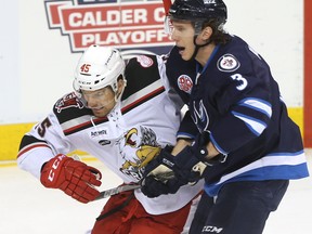 Grand Rapids Griffins Colin Campbell (left) and Manitoba Moose Jan Kostalek battle for the puck in Game 1 of the AHL playoffs Saturday.