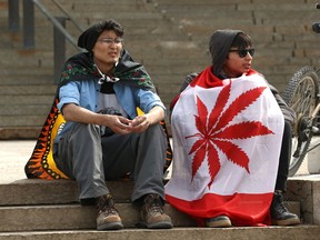 A participant is wrapped in an O Cannabis flag during the 4/20 event on the Manitoba Legislative Building grounds