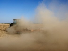 Dust billows as a farmer plows a dry field.
Getty Images