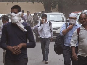 In this Wednesday, May 2, 2018 file photo, people cover their noses as a dust storm envelops the city in New Delhi, India. A powerful dust storm and rain swept parts of north and western India overnight, causing house collapses, toppling trees and leaving dozens dead and more than 160 injured, officials said Thursday.