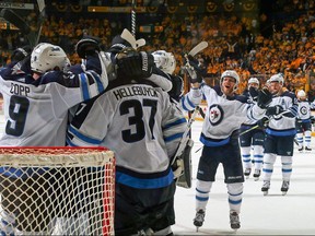 Jets players rush to congratulate goaltender Connor Hellebuyck near his crease following Thursday night’s series-clincher agianst the Preds in Nashville. (GETTY IMAGES/PHOTO)