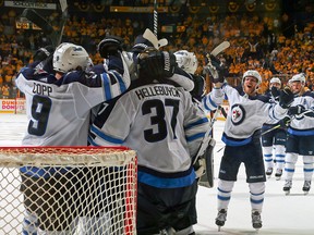 Jets players rush to congratulate goaltender Connor Hellebuyck near his crease following Thursday night’s series-clincher agianst the Preds in Nashville. (GETTY IMAGES/PHOTO)