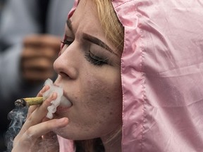 A woman exhales while smoking a joint during the 4/20 annual marijuana celebration, in Vancouver, B.C., on Friday April 20, 2018. THE CANADIAN PRESS/Darryl Dyck