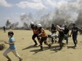 Palestinian medics and protesters evacuate a wounded youth during a protest at the Gaza Strip's border with Israel, east of Khan Younis, Gaza Strip, Monday, May 14, 2018. Thousands of Palestinians are protesting near Gaza's border with Israel, as Israel prepared for the festive inauguration of a new U.S. Embassy in contested Jerusalem.