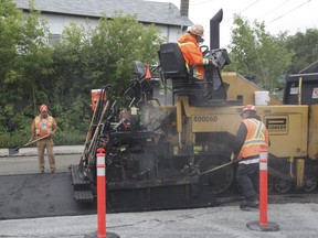 A paving crew hard at work laying asphalt. Drivers are reminded that sometimes roads are workplaces too.