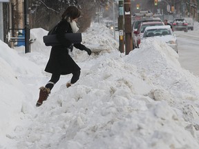 A woman climbs a pile of snow after snow clearing crews dumped snow on the sidewalk in Winnipeg.
Winnipeg Sun Files