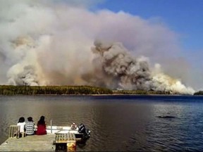 People from the Pauingassi First Nation watch a fire burning in Little Grand Rapids, Man. in a handout photo provided by councillor Clinton Keeper of Little Grand Rapids.THE CANADIAN PRESS/ HO-Clinton Keeper
