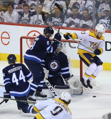 Nashville Predators forward Viktor Arvidsson (right) jumps to avoid a shot in front of Winnipeg Jets goaltender Connor Hellebuyck during Game 4 of their second-round NHL playoff series in Winnipeg on Thurs., May 3, 2018. Kevin King/Winnipeg Sun/Postmedia Network