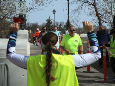 A volunteer cheers for runners as they cross the Assiniboine Park foot bridge during the Winnipeg Police Service half marathon in Winnipeg on Sun., May 6, 2018. Kevin King/Winnipeg Sun/Postmedia Network