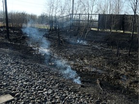 Areas smoulder near the Shaftesbury Park Retirement Residence from what police called a brush fire near the intersection of Sterling Lyon Parkway and Shaftesbury Boulevard in Winnipeg on May 6. Canadian National Railway says it's sending a cheque to the City of Winnipeg to cover firefighting costs after a series of brush fires suspected of being caused by a CN train.