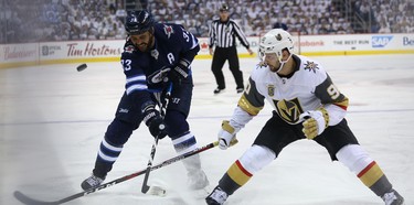 Winnipeg Jets defenceman Dustin Byfuglien whacks the puck in the Vegas Golden Knights zone as Tomas Tatar defends during Game 2 of the Western Conference final in Winnipeg on Mon., May 14, 2018. Kevin King/Winnipeg Sun/Postmedia Network