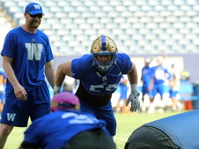 Adam Bighill lines up a tackling dummy with head coach Mike O'Shea smiling behind him during Winnipeg Blue Bombers training camp in Winnipeg on Sun., May 27, 2018. Kevin King/Winnipeg Sun/Postmedia Network