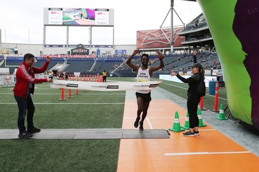 Abduselam Yussuf of Winnipeg runs through the finish line tape to win the men's half marathon at the 40th annual Manitoba Marathon in Winnipeg, Man., on Sunday, June 17, 2018. Pictured: City of Winnipeg Mayor Brian Bowman and Manitoa Marathon Foundation executive director Rachel Munday hold the tape as Yussuf finishes in first in the 13.1 mile race in a time of 1:08:30.0. (Brook Jones/Postmedia Network)