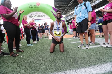 Abduselam Yussuf of Winnipeg is surrounded by plenty of cheers as he kneels after winning the men's half marathon at the 40th annual Manitoba Marathon in Winnipeg, Man., on Sunday, June 17, 2018. Yussuf crossed the finish line in the 13.1 mile race in a time of 1:08:30.0. (Brook Jones/Postmedia Network)
