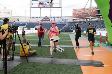 Darolyn Walker of Winnipeg runs through the finish line tape to win the women's half marathon at the 40th annual Manitoba Marathon in Winnipeg, Man., on Sunday, June 17, 2018. Walker won the 13.1 mile race in a time of 1:25:17.3. (Brook Jones/Postmedia Network)