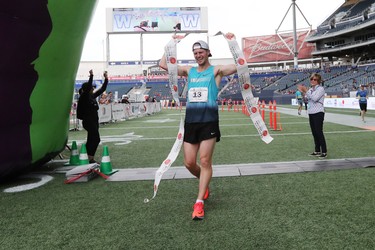 Corey Gallagher holds up the finish line tape after winning the men's full marathon at the 40th annual Manitoba Marathon in Winnipeg, Man., on Sunday, June 17, 2018. Callagher crossed the finish line in the 26.2 mile race in a time of 2:37:47.6. (Brook Jones/Postmedia Network)