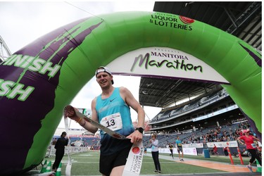 Corey Gallagher holds the finish line tape after winning the men's full marathon at the 40th annual Manitoba Marathon in Winnipeg, Man., on Sunday, June 17, 2018. Callagher crossed the finish line in the 26.2 mile race in a time of 2:37:47.6. (Brook Jones/Postmedia Network)