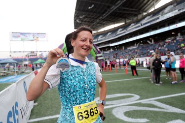 Tracey Hofer of Westbourne, Man., shows off her finisher medal after competing in the half marathon at the 40th annual Manitoba Marathon in Winnipeg, Man., on Sunday, June 17, 2018. (Brook Jones/Postmedia Network)