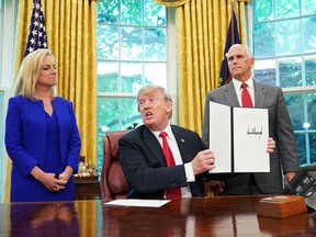 Watched by Homeland Security Secretary Kirstjen Nielsen (L) and Vice President Mike Pence, US President Donald Trump holds an executive order on immigration which he just signed in the Oval Office of the White House on June 20, 2018 in Washington, DC.
