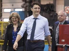 Prime Minister Justin Trudeau and local candidate Lina Boivin, left, visit a machine shop, Thursday, June 14, 2018 in Saguenay Que.