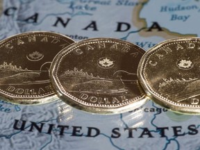 Canadian dollar coins are displayed on a map along the border of Canada and the United States of America, in Montreal in a January 9, 2014, file photo. With volatility spikes hammering global equity markets over the past week, the Canadian dollar has been in free fall -- leaving many investors wondering how far the loonie will drop. THE CANADIAN PRESS/Paul Chiasson ORG XMIT: CPT502