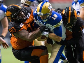 Winnipeg Blue Bombers quarterback Alex Ross, (centre) is sacked by B.C. Lions' Odell Willis (right) as Davon Coleman helps bring him down during  CFL pre-season action in Vancouver on Friday. (The Canadian Press)