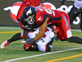 The Calgary Stampeders' Ja'Gard Davis and James Vaughters sack Ottawa Redblacks quarterback Trevor Harris during CFL action at McMahon Stadium in Calgary Thursday night. (Gavin Young/Postmedia Network)