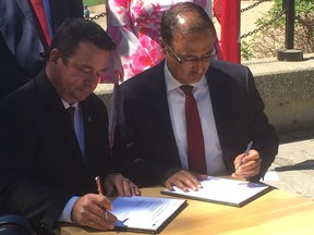 Jeff Wharton, provincial Minister of Minicipal Relations, (left) and Amarjeet Sohi, federal Minister of Infrastructure and Communities, sign a bilateral agreement between the federal and provincial governments to make long-term infrastructure investments at a press conference on Monday at The Forks.