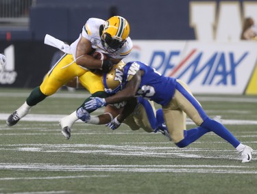 Calvin McCarty (31) gets hit by Winnipeg Blue Bombers' Anthony Gaitor (23), and another Bomber during CFL action in Winnipeg today.   Thursday, June 14, 2018.   Sun/Postmedia Network