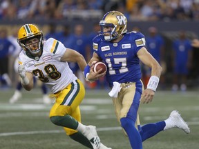 Winnipeg Blue Bombers' quarterback Chris Streveler (17) slips past Edmonton Eskimos' Adam Konar (38) during CFL action in Winnipeg today.   Thursday, June 14, 2018.   Sun/Postmedia Network