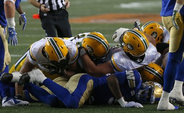 Winnipeg Blue Bombers DE Tristan Okpalaugo is at the bottom of the pile as Edmonton Eskimos QB Mike Reilly (centre) carries the ball for a touchdown during CFL action in Winnipeg on Thurs., June 14, 2018. Kevin King/Winnipeg Sun/Postmedia Network