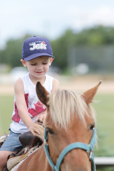 Two-year-old Liam is seen riding a pony named Bell during the Canada Day celebrations at the Sunova Centre in the RM of West St. Paul, Man., north of Winnipeg, Man., on Sunday, July 1, 2018. Pictured: L-R: Sarah Petrie, Hannah Leary and Julia Daterra. (Brook Jones/Selkirk Journal/Postmedia Network)