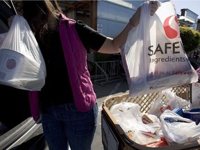A woman loads groceries in Safeway plastic bags into her car.