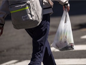 A shopper leaves a store carrying a plastic shopping bag.