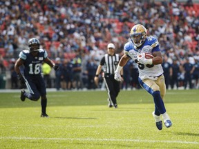 Toronto Argonauts Eric Striker, left, looks on as Winnipeg Blue Bombers' Andrew Harris scores a touchdown during first half CFL football action in Toronto on Saturday, July 21, 2018. THE CANADIAN PRESS/Mark Blinch ORG XMIT: MDB121