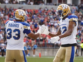 Winnipeg Blue Bombers' Andrew Harris celebrates his touchdown with teammate Adarius Bowman against the Toronto Argonauts, in Toronto on Saturday.