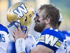 Winnipeg Blue Bombers quarterback Chris Streveler (17) pauses while putting his helmet back on shortly after being hit hard on a previous play during first quarter CFL game action against the Hamilton Tiger-Cats in Hamilton, Ontario on Friday, June 29, 2018. THE CANADIAN PRESS/Peter Power ORG XMIT: pmp146