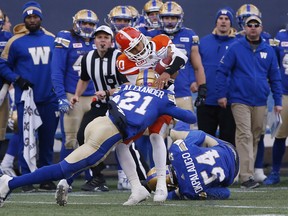 Blue Bombers’ Brandon Alexander (left) hits B.C. Lions quarterback Jonathon Jennings as he tries to run for yards. The CFL has taken steps to educate its players on recognizing concussion symptoms.  John Woods/The Canadian Press