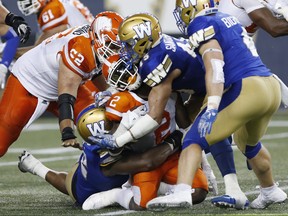 B.C. Lions' Chris Rainey (2) runs into Winnipeg Blue Bombers' Jovan Santos-Knox (45) during the second half of CFL action in Winnipeg Saturday.