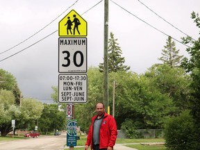St. Norbert-Seine River candidate Chris Davis stands at a reduced speed limit sign in a school zone in St. Norbert. (Photo courtesy of Trielle Photography)