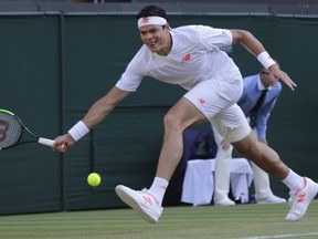 Milos Raonic returns the ball to John Isner during their men's quarterfinal match at Wimbledon, in London, Wednesday July 11, 2018.