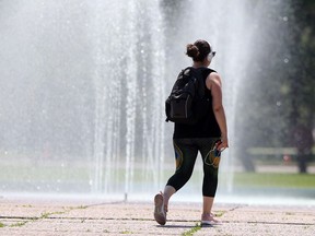 A pedestrian elects to walk past a public fountain during a very hot day in Winnipeg. Saturday.