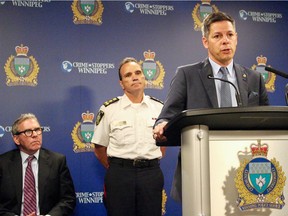 Mayor Brian Bowman speaks to the media with Winnipeg police Chief Danny Smyth (centre) and Winnipeg Police Board Chair David Asper (left) at police headquarters in Winnipeg following the release of the Winnipeg police's crime statistics for 2017.