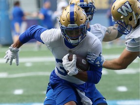 Andrew Harris carries the ball while teammates try to rip it away from him during Winnipeg Blue Bombers practice on Tuesday.