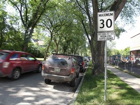 A vehicle passes a school zone speed limit sign. The City is studying whether to lower the speed on all residential streets to 30 km/h, instead of 50 km/h.