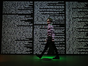 A staff member stands in a projection of live data feeds from (l-r) Twitter, Instagram and Transport for London by data visualisation studio Tekja at the Big Bang Data exhibition at Somerset House on December 2, 2015 in London, England. The show highlighted the data explosion that's radically transforming our lives.