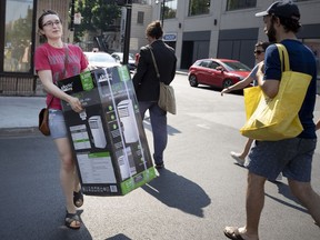 Michelle St. Pierre carries an air conditioner to the bus stop as Montreal endures a heat wave in Montreal.