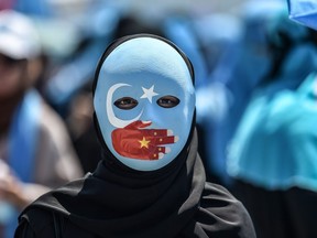 A demonstrator wearing a mask painted with the colours of the flag of East Turkestan and a hand bearing the colours of the Chinese flag attends a protest of supporters of the mostly Muslim Uighur minority and Turkish nationalists to denounce China's treatment of ethnic Uighur Muslims during a deadly riot in July 2009 in Urumqi, in front of the Chinese consulate in Istanbul, on July 5, 2018. Nearly 200 people died during a series of violent riots that broke out on July 5, 2009 over several days in Urumqi, the capital city of the Xinjiang Uyghur Autonomous Region, in northwestern China, between Uyghurs and Han people. OZAN KOSE/AFP/Getty Images