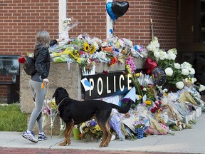 Flowers are placed on a makeshift memorial outside the police station in Fredericton on Saturday, Aug. 11, 2018. (THE CANADIAN PRESS/Andrew Vaughan)