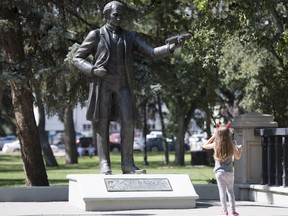 A little girl stops to look at a statue of John A. Macdonald.